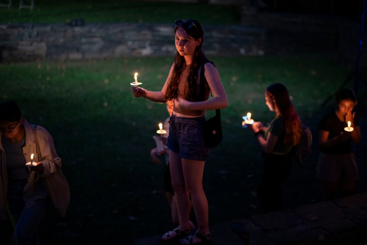 Student holds candle in amphitheater during First Collection