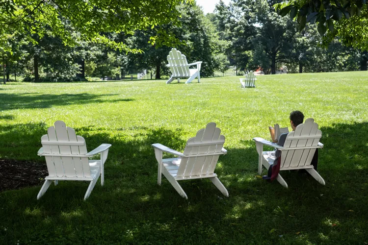 Person reads on white Adirondack chair on Parrish Beach