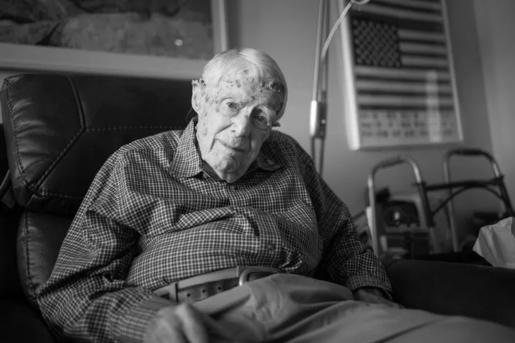 Black and white photo of old man sitting on couch