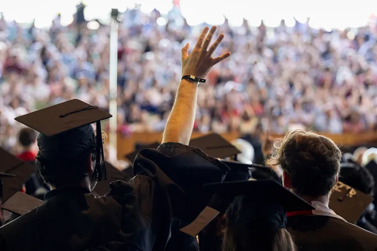 Students cross stage during commencement at Mann Center