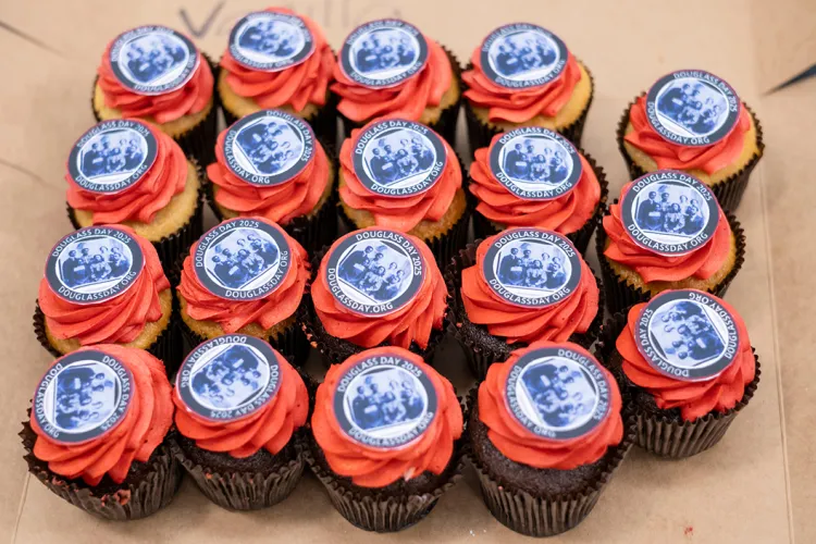 Chocolate cupcakes with red frosting and Douglass Day 2025 toppers