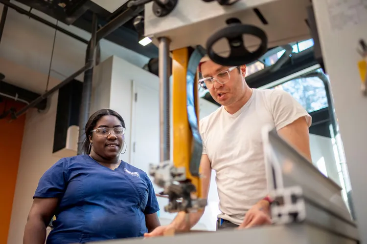 Two people use wood cutter in makerspace lab