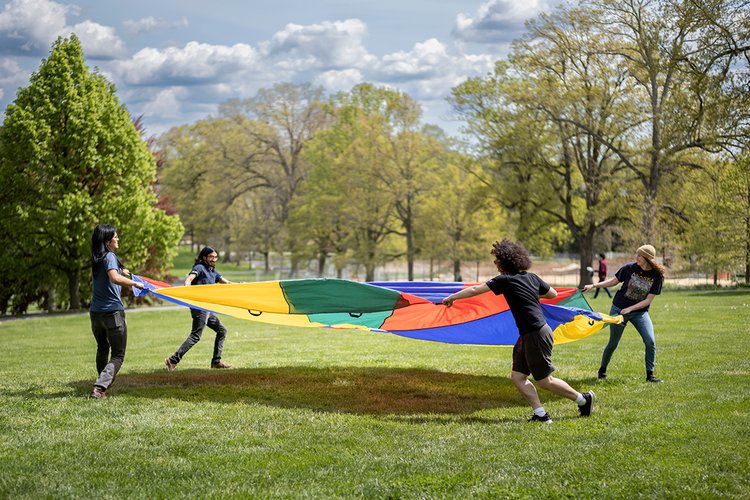 People hold multicolor parachute outside