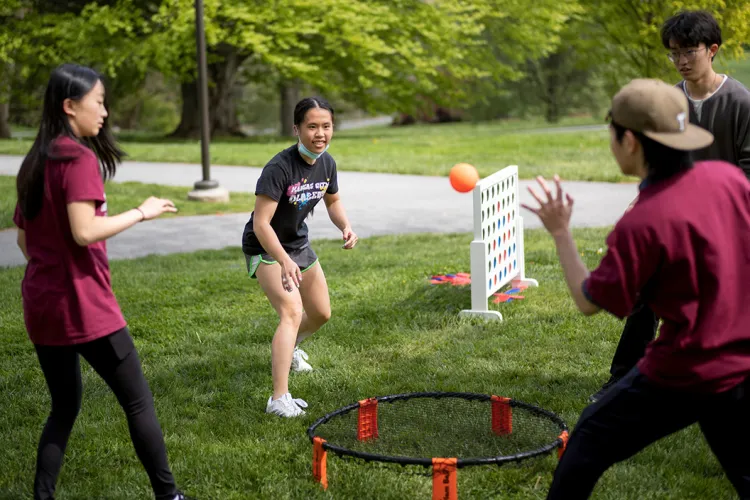 Students stand around Spikeball net