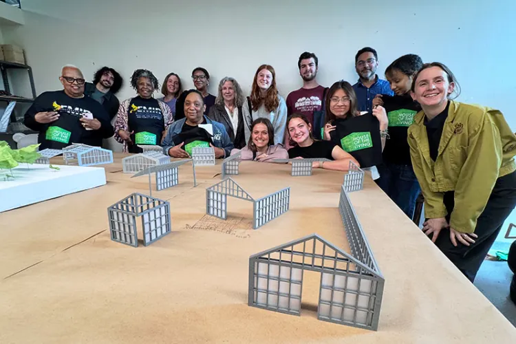 People gathered around table with models of plastic homes
