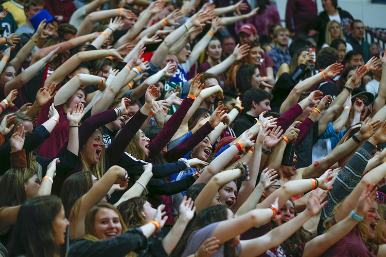 Basketball fans lean to right with arms in the air