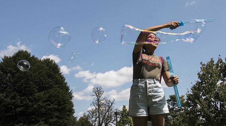 Student uses bubble wand outside during summer