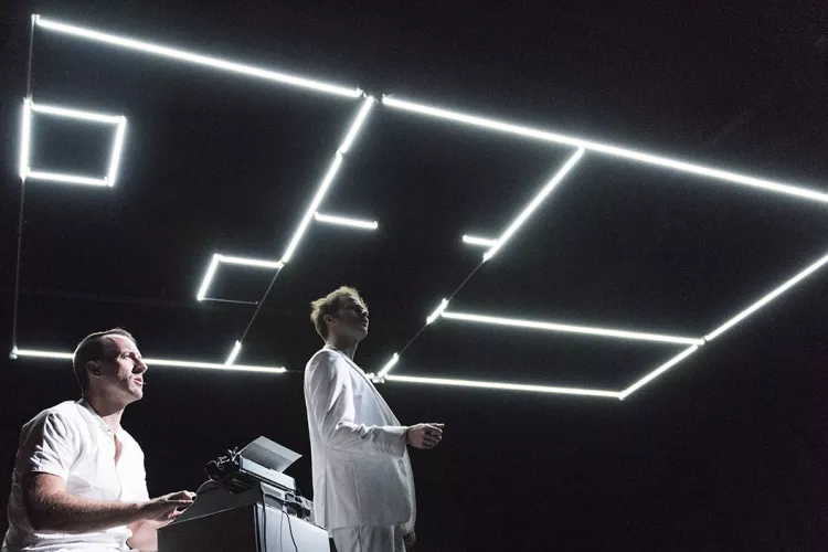 Two men in dark room with white lights