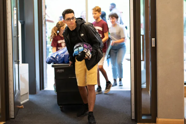Student pushes cart with belongings into dorm