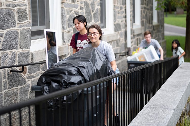 Student pushes cart with belongings into dorm