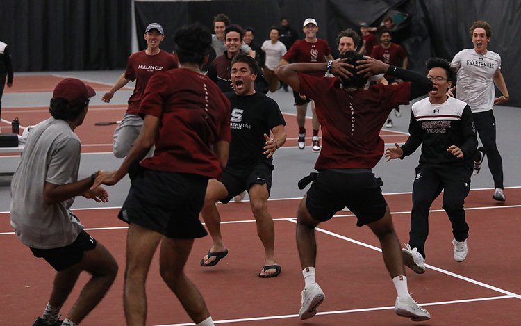 Tennis team members rush onto court to celebrate winning conference championship.