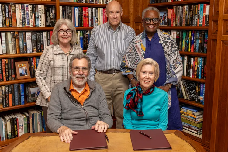 Shankers at signing ceremony table with members of College leadership standing behind them