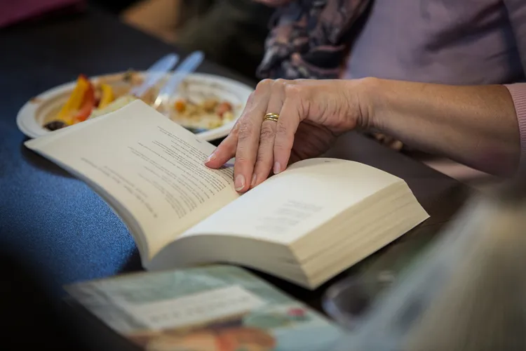 Person's hand turns pages of a book on a table