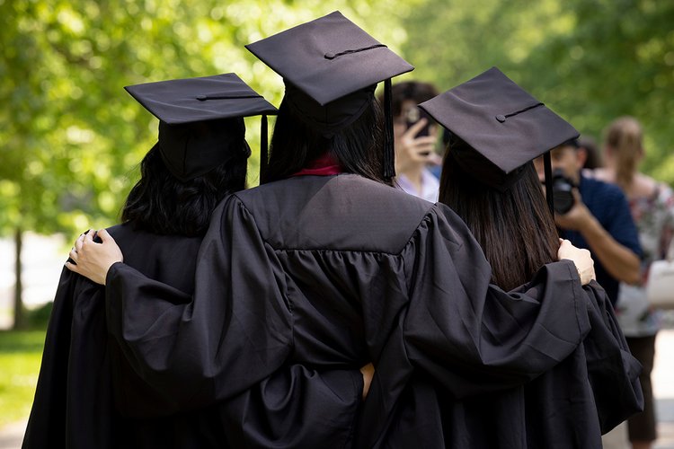 Students wearing caps and gowns take group picture