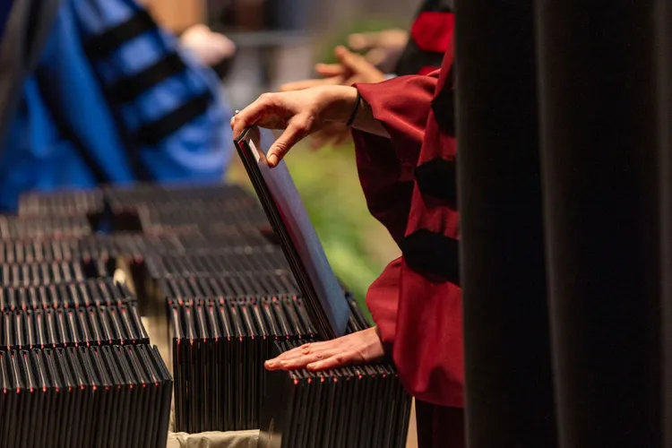 Stack of diplomas on table as unseen person sorts through them