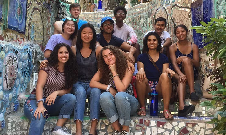 The Chester Fellows sit together on steps at Philadelphia's Magic Garden