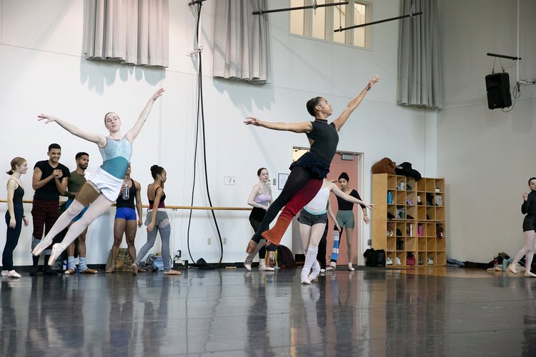 Two dancers jump during rehearsal