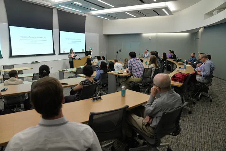 Group of participants at macroeconomics conference sit in classroom and listen to lecture