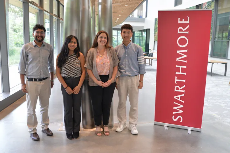 Group of participants at econ conference pose with red Swarthmore banner
