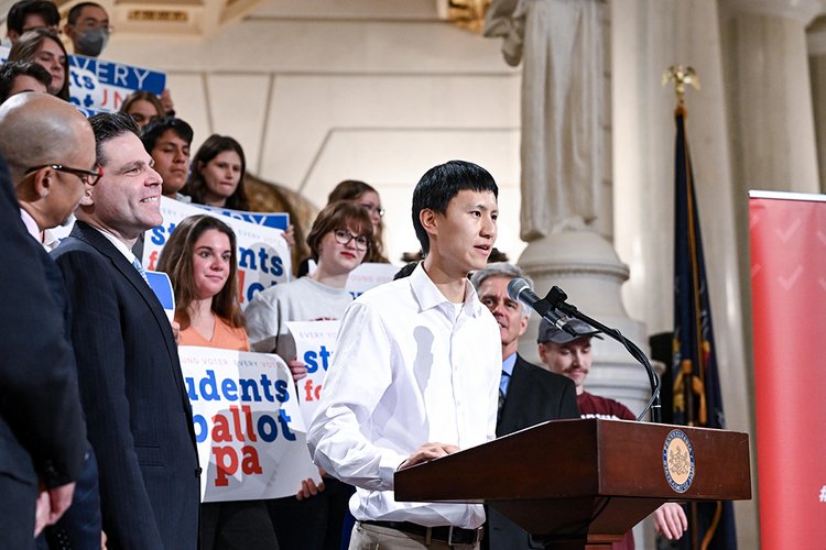 Harry Hou at podium speaking in front of Jared Solomon and students gathered for ballot reform