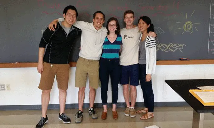 A group of students pose for a photo in front of a chalboard