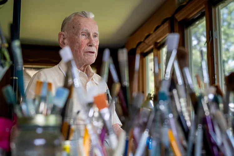 Morton Huber at home with paint brushes in foreground