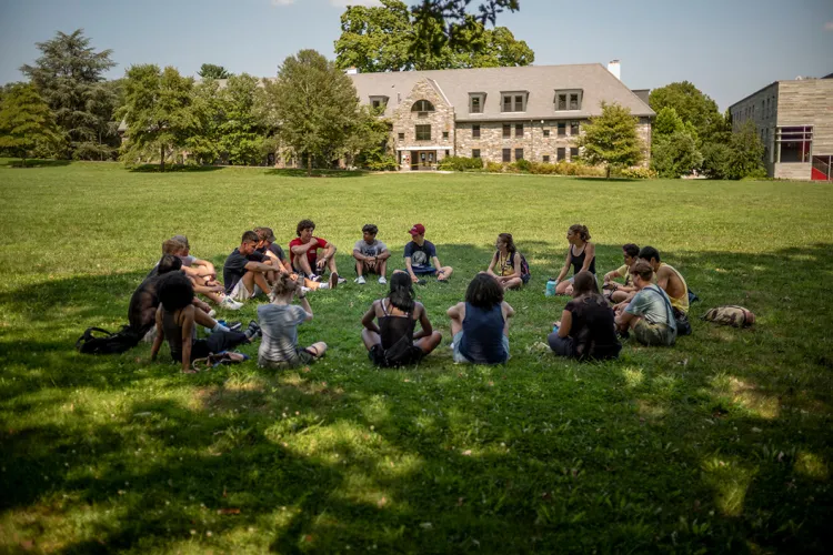 Students sit in circle on outdoor lawn