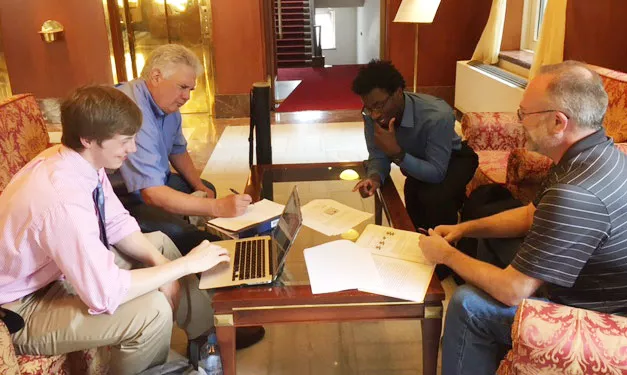 students and professors sitting around a tale
