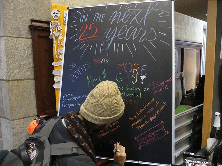 student writes on a blackboard