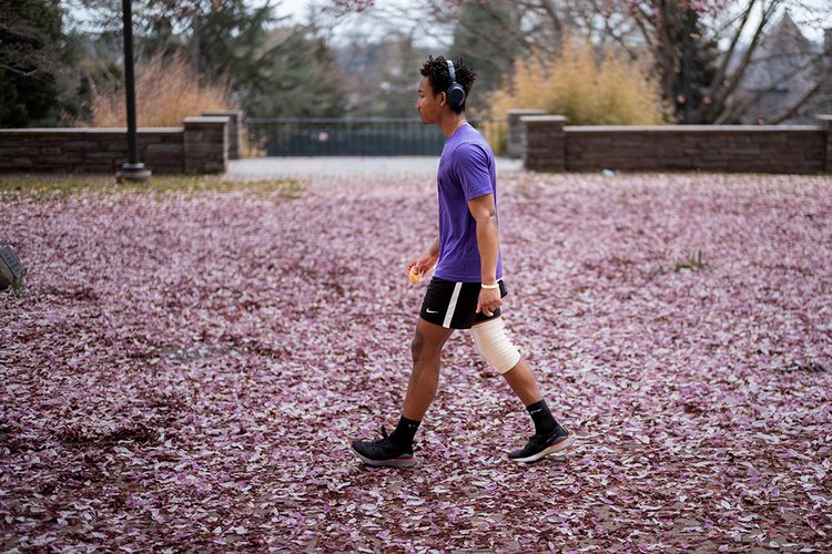 Student walks on flower petals in Wharton Courtyard
