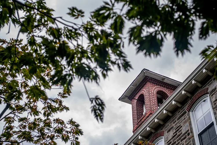 Upward facing shot of brick building with small belltower at top of frame.