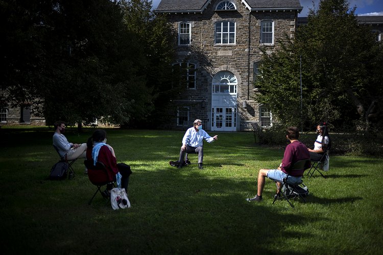 Seated professor teaches small class outdoors