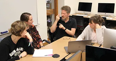 Students use sign language with each other while working at computers