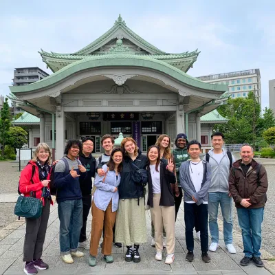 Group of students and faculty stand in front of a Japanese temple