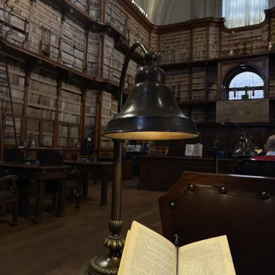 Book sits open in the foreground of historic library with tall stacks