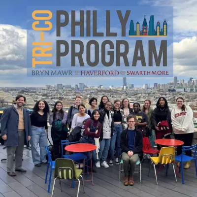 Group of students stand on rooftop with philly skyline behind them