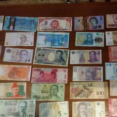 Paper currency from around the world lead out on wooden table