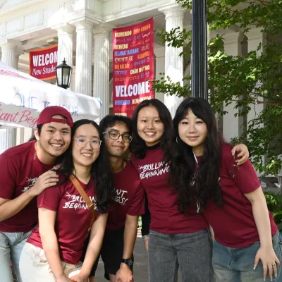 Group of college co-eds huddles in front of welcome banners