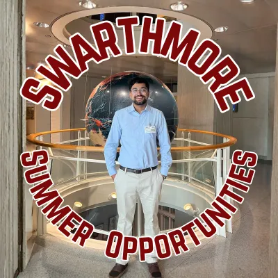 Professionally dressed male student stands in front of globe sculpture