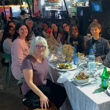 Group sits for meal at long table with white tablecloth