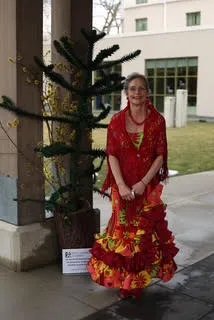 Woman in flowered red dress standing by a pillar.