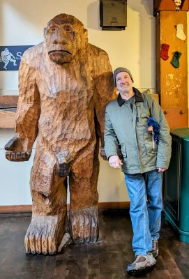 Man standing next to a statue of Sasquatch