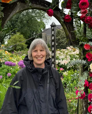 Woman standing under a trellis of roses