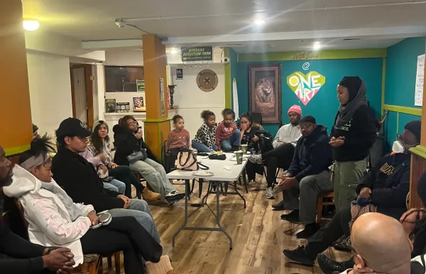 Image of a group of people of diverse ages gathered around a table in a classroom