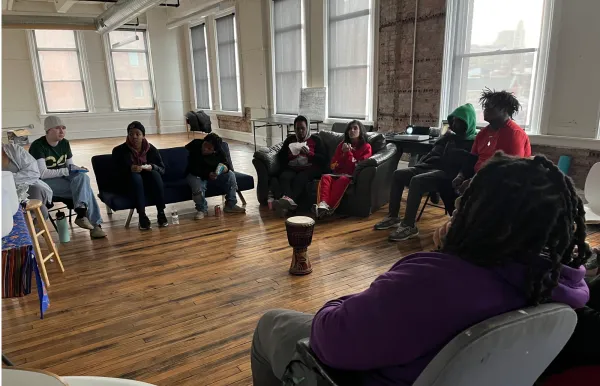 People gathered in a circle around a drum