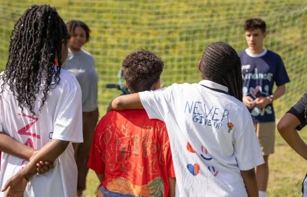 Image of Omri Gal speaking to Design FC students, with their backs to camera wearing a jersey that says "Never Give Up"
