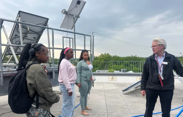 Image of Professor Everbach showing students solar panels on top of Singer roof