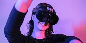 Emerging Technologies Fellow Liz Hogrefe against a purple background wearing a VR headset and waving her arms