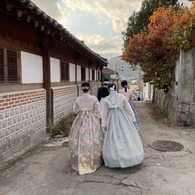 2 female students wearing traditional korean dress walk away from the camera
