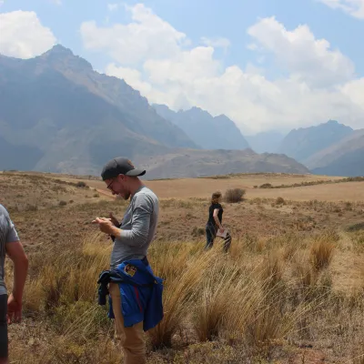 Two students stand in grasslands collecting samples for field research